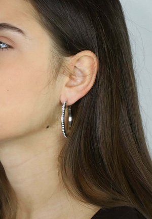 Boucles d'oreilles créoles en argent avec une finition polie, ornées d'une rangée de petits gemmes clairs le long du bord extérieur, affichant un design élégant.