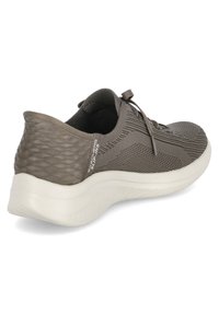 Sneaker grigia in rete con un design testurizzato, suola bianca arrotondata e lacci piatti. Presenta un accento con marchio sul retro.