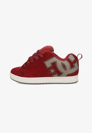 Roter Sneaker in niedriger Ausführung mit grauem DC-Logo an der Seite, roten Schnürsenkeln, weißer Sohle und Zuglasche an der Ferse.