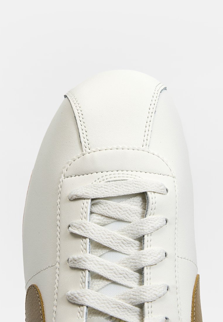 Weißes Leder-Sneaker mit abgerundetem Zehenbereich, strukturierten Schnürsenkeln und hellbraunen Akzenten an der Seite. Verfügt über eine glatte Oberfläche und genähte Details.