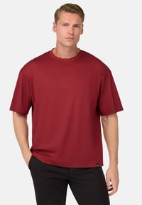 T-shirt a maniche corte bordeaux in tessuto morbido con collo tondo e vestibilità rilassata, caratterizzata da un piccolo etichetta con logo sul lato inferiore.