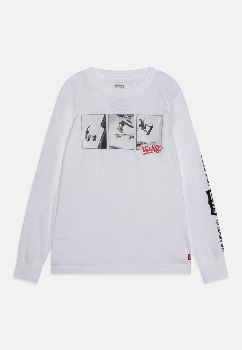 Biała koszula z długim rękawem z trzema czarno-białymi zdjęciami skateboardingu na wysokości klatki piersiowej oraz czerwonym logo "Levi's" poniżej prawego zdjęcia.