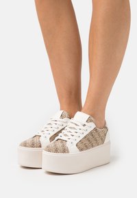 Sneaker marroni con motivo, dotati di suola piatta bianca, con lacci bianchi e dettagli a contrasto. Parte superiore in tessuto testurizzato con logo.