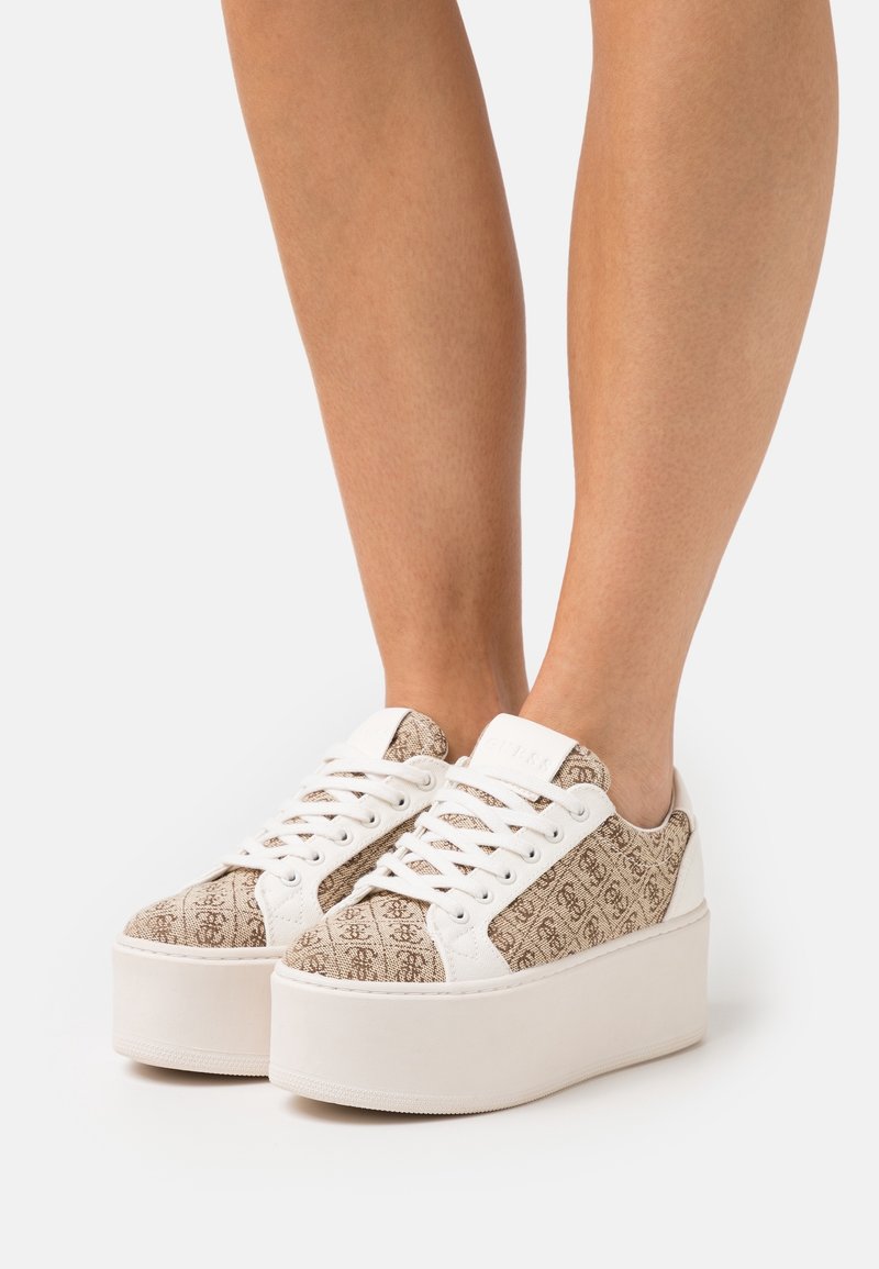 Sneaker marroni con motivo, dotati di suola piatta bianca, con lacci bianchi e dettagli a contrasto. Parte superiore in tessuto testurizzato con logo.