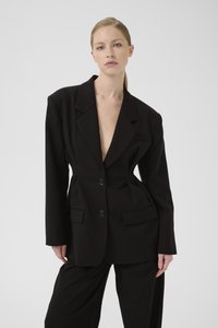 Svart oversized blazer med spisse slag, to frontlommer og dobbel knappelukking. Glatt stoff med en strukturert silhuett.