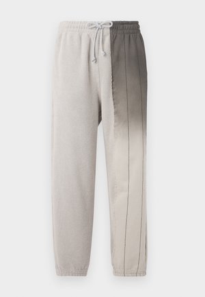 Helle graue Jogginghosen mit einem Kordelzugbund, weichem Material und einem Farbverlauf von hell- nach dunkelgrau mit vertikalen Steppnähten.