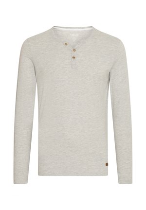 Jasnoszara koszula z długimi rękawami, wykonana z miękkiego materiału, z okrągłym dekoltem, trzema drewnianymi guzikami i małą brązową naszywką z logo u dołu.