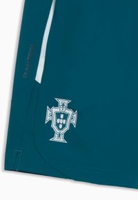 Shorts de sport bleu sarcelle avec bande latérale blanche, texte PUMA TECH sur la gauche, et blason FPF comprenant un écusson avec cinq petits écussons disposés en croix.