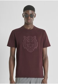 Bordo majica kratkih rukava od pamuka s istaknutim reljefnim dizajnom tigrove glave na prednjem dijelu. Klasičan okrugli izrez.