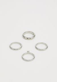 Fire sølvringer utstilt på en enkel overflate. Ringene varierer i design: en har en fremtredende midtsten, mens de andre er glatte bånd.