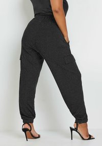 Svarta, glittrande joggerbyxor har en elastisk midja, sidofickor och smalnande muddar, vilket ger en avslappnad passform och en casual stil.