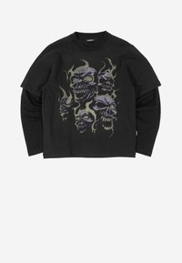 Fekete, réteges, hosszú ujjú póló, elöl öt lila koponya grafika látható sárgászöld lángokkal körülvéve.