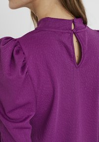 Lila strukturierte Bluse mit puffärmel und einem Schlüsselloch-Detail am Rücken. Glatte Stoff mit einer sanften Oberfläche.