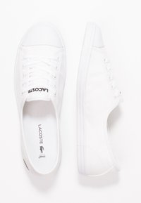 Baskets en toile blanche avec embout en caoutchouc, design à lacets et marquage discret. Dotées d'une semelle texturée pour une meilleure adhérence.