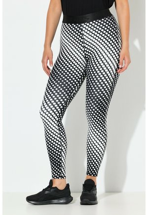 Leggings med høj talje, sort og hvidt diagonalt polkaprikket mønster, båret med sorte sneakers og sort top.