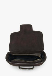 Hnědá semišová kabelka s pevnějším tvarem, vybavená zapínáním na klopu, vnitřní kapsou na zip a kontrastní světlou kovovou výbavou.
