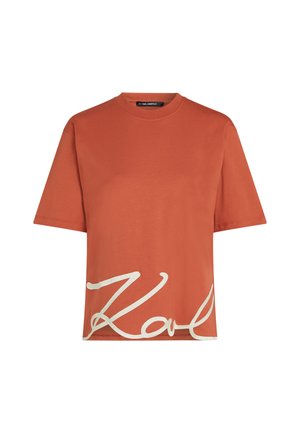 Rust-colored cotton t-shirt with short sleeves and a round neck, featuring white "Karl" signature graphic on the front. Smooth texture.