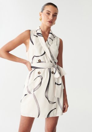 Weißes ärmelloses Kleid mit schwarzen abstrakten Mustern, doppelter Knopfleiste, tailliertem Gürtel und Schalkragen. Glatte Stoffoberfläche.