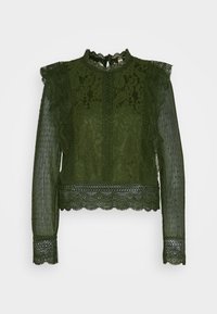 Blusa verde in pizzo con maniche lunghe e aderenti, colletto alto e orlo ondulato. Presenta motivi floreali e accenti di tessuto testurizzato.
