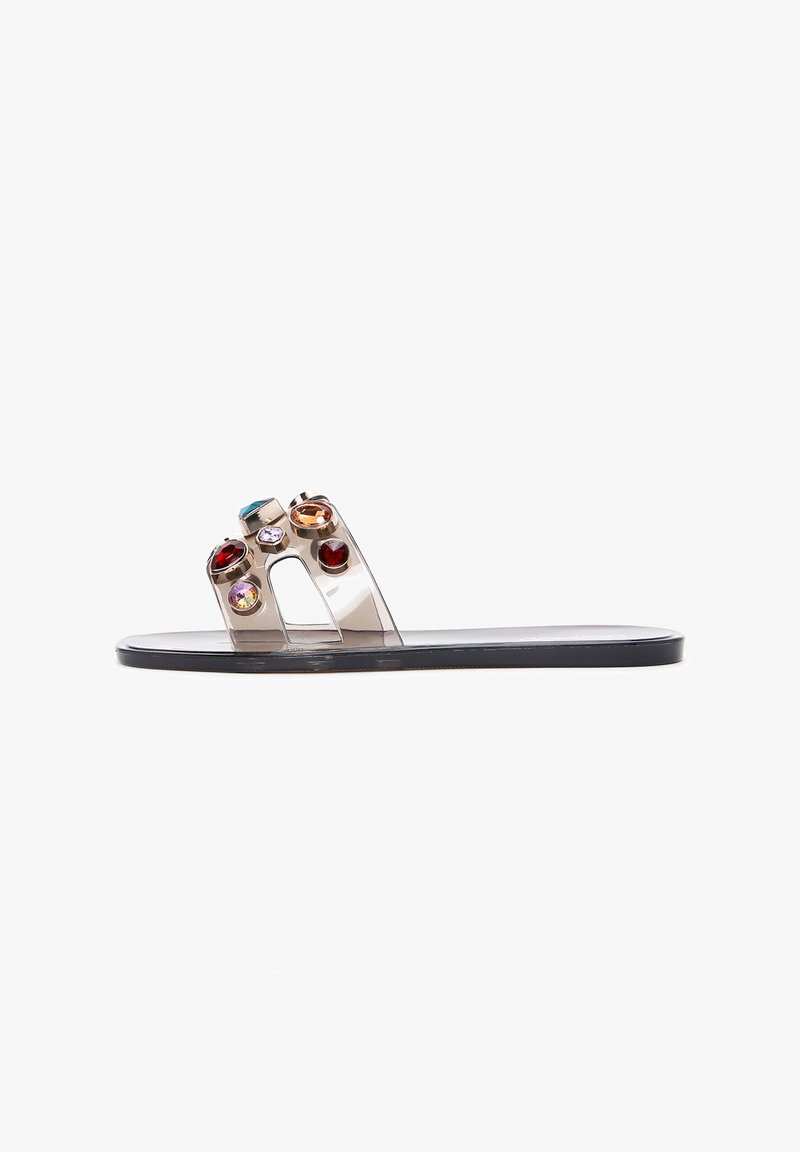 Transparent slide sandals with a black sole, featuring multiple colorful gemstones on the upper section in various shapes and sizes.