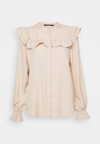 Blouse beige avec un col à volants, une fermeture à boutons et des poignets froncés. Confectionnée dans un tissu lisse avec une coupe décontractée.