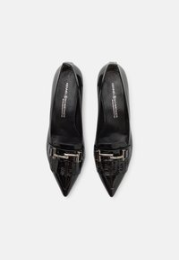 Paire de ballerines en cuir verni noir à bout pointu pour femmes, avec boucle argentée et détail texturé à l'avant, vue de dessus.