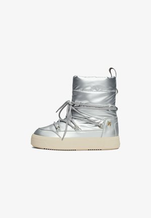 Srebrne ocieplane botki za kostkę o gładkim metalicznym wykończeniu, sznurowane z przodu, z gumową podeszwą oraz detalem w postaci bocznego suwaka. Posiadają pętelkę ułatwiającą zakładanie.