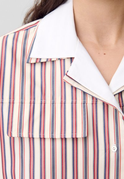 Camisa a rayas con rayas verticales en rojo, azul y crema. Incluye un collar blanco y un bolsillo en el pecho con un detalle de botón.