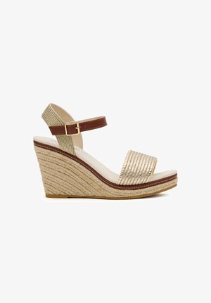 Sandalia con cuña tejida en beige con tiras marrones en el tobillo y hebilla, puntera abierta y suela de cuerda texturizada, mostrada de perfil sobre fondo blanco.