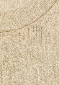 Strickstoff in hellbeige mit einem strukturierten Muster und einem gerippten Rundhalsausschnitt, der feine Linien und eine glatte Oberfläche aufweist.