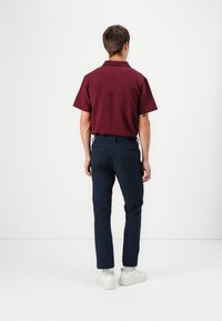 Maroon short-sleeve shirt with textured pattern, paired with navy slim-fit trousers and white sneakers, viewed from the back.