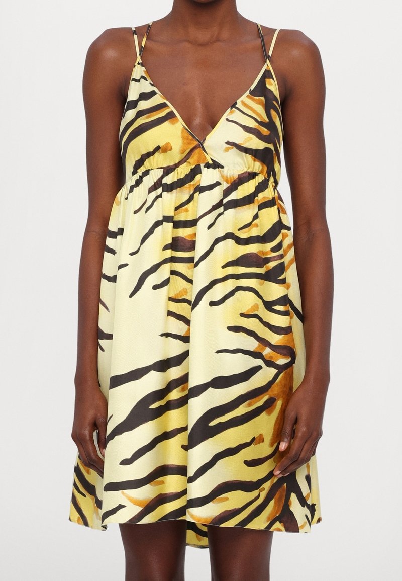 Robes jaunes avec des rayures de tigre noires et orange. Comprend des bretelles ajustables et une taille froncée, s'évasant jusqu'à un ourlet au niveau des genoux.