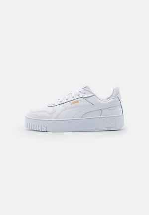 Baskets basses blanches Puma avec semelle épaisse, lacets à l'avant et logo Puma doré sur le côté, vues de profil intérieur.