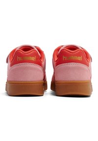 Rosa mockaskor med en texturerad mesh-övre och gummigummisula. Har en gyllene "hummel"-logotyp på baksidan och justerbart spänne.