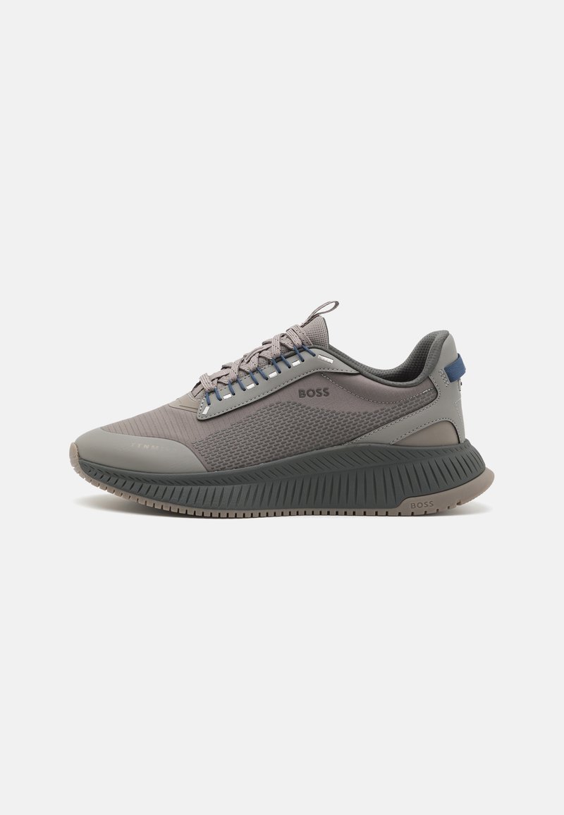Baskets de sport grises avec tige texturée, semelle épaisse rainurée, fermeture à lacets et marquage "BOSS" sur le côté et la semelle.