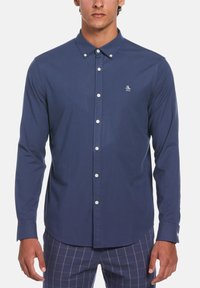 Navy blue long-sleeve button-up shirt with a pointed collar, white buttons, and a small penguin logo embroidered on the chest.