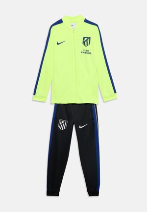 Veste jaune néon avec des rayures bleues et pantalon noir avec les logos Atlético Madrid et Nike, et texte "Visit Rwanda" sur la veste.