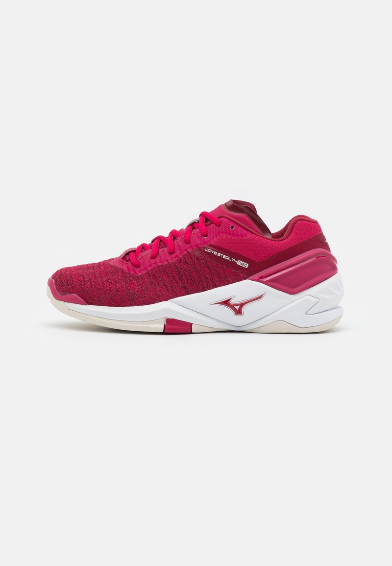 Chaussure de sport rouge avec semelle blanche, empeigne en mesh, lacets et logo sur le côté, positionnée de profil sur un fond blanc uni.