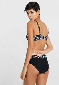 Blomsterbikini med svart bas, som har en mönstrad topp och en enfärgad svart högmidjad botten. Justerbara axelremmar och detalj med spänne.
