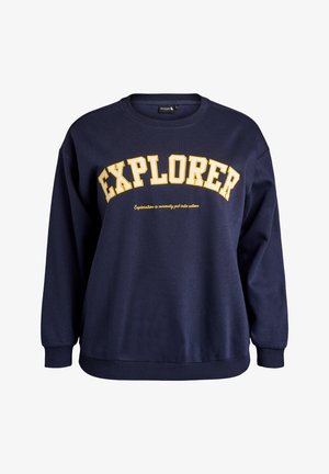 Tumedat sinine sviiter pikade varrukatega, soonikkoes ja -alus. Rinnal ääretu kollase kirjaosaga "EXPLORER" ja allpool slogan.