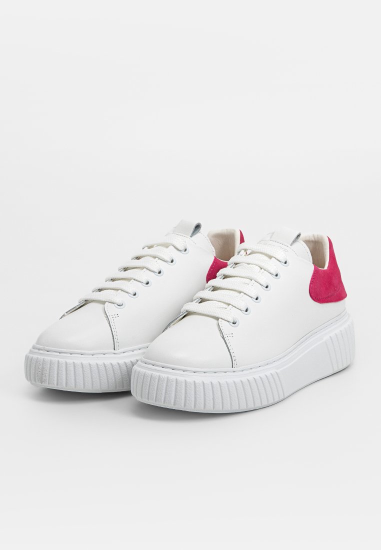 Weiße Sneaker mit einem glatten Lederoberteil, pinkem Wildlederakzent an der Ferse und dicker Gummi-Außensohle mit vertikalen Rillen.