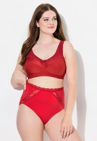 Rood lingerie set met een getextureerde beha met brede bandjes en een strikdetail, gecombineerd met hooggeremde slips versierd met kant.