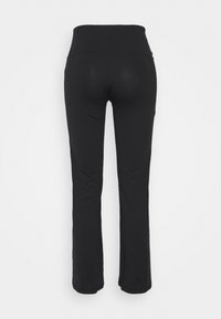 Pantalon de yoga noir taille haute, ajusté avec une jambe légèrement évasée, vu de dos sur un fond uni.