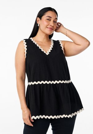 Top negro sin mangas con escote en V, que presenta un ribete con volantes en color crema a lo largo de los bordes y una silueta de peplum. La textura parece ligera.