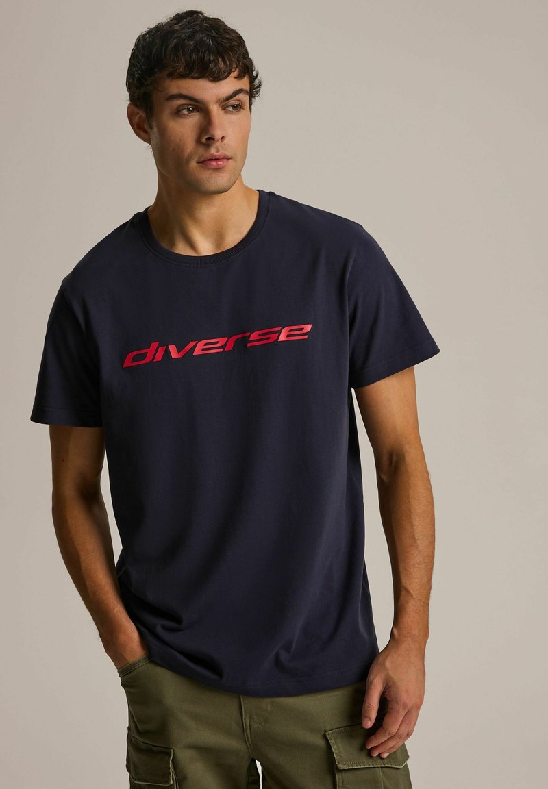 Granatowa bawełniana koszulka z wyraźnym czerwonym logotypem "diverse" na piersi, klasyczny okrągły dekolt i krótkie rękawy.