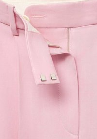 Lichtroze stoffen broek met een tailleband sluiting met twee zilveren metalen haken en een gedeeltelijk open rits.