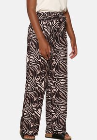 Wide-leg trousers in a zebra print pattern, featuring shades of dark brown and light beige, with a tied waist and soft fabric texture.