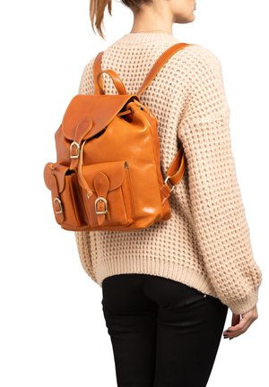 Zaino in pelle di un caldo arancione, con patta pieghevole, due tasche frontali e hardware argentato. Indossato sulla schiena con spallacci regolabili.