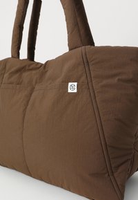 Borsa tote marrone trapuntata con tessuto testurizzato, manici doppi e una toppa con logo bianco. Presenta un design strutturato e angolare.