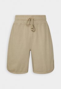 Pantalones cortos de algodón beige con cinturilla elástica y cordón, que presentan un corte holgado y aberturas laterales para facilitar el movimiento.